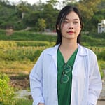 A woman in a lab coat standing in a field