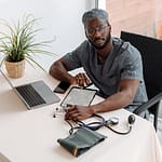 Man Sitting on a Chair infront of a Table with Laptop and Tablet